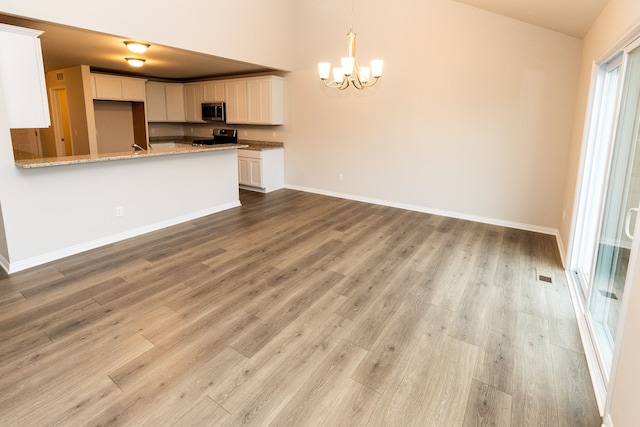 kitchen with stainless steel appliances, white cabinetry, light wood-style flooring, and light stone countertops