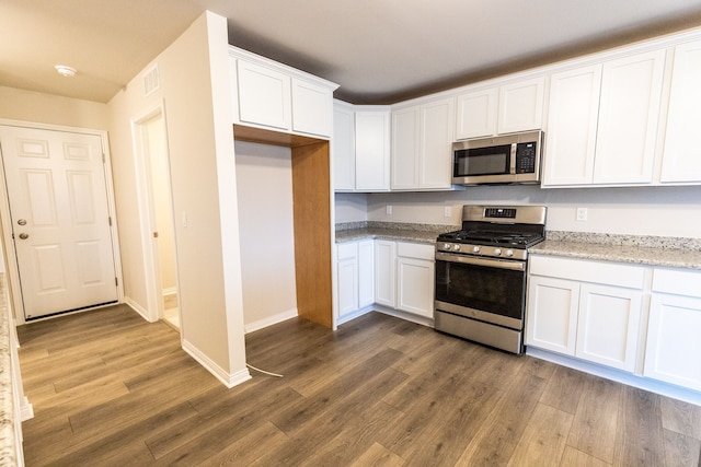 kitchen with stainless steel appliances, wood finished floors, white cabinetry, and light stone countertops