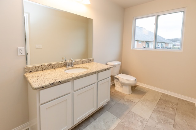 half bathroom with toilet, vanity, and baseboards