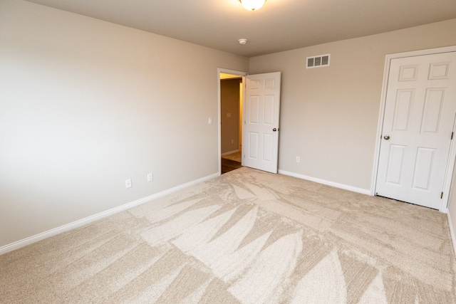 unfurnished room with baseboards, visible vents, and light colored carpet