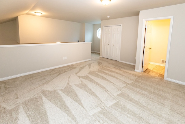 unfurnished room featuring baseboards, vaulted ceiling, visible vents, and light colored carpet