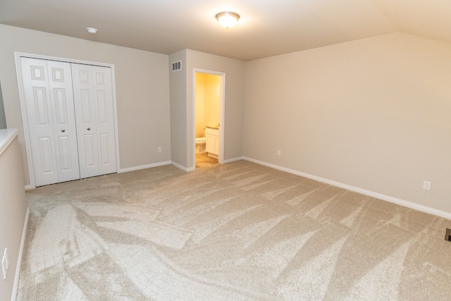 unfurnished bedroom featuring light carpet, lofted ceiling, visible vents, and baseboards