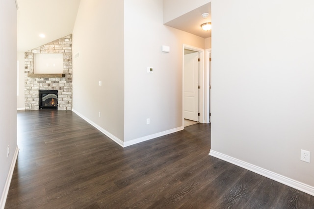 unfurnished living room with dark wood-style floors, a fireplace, baseboards, and vaulted ceiling