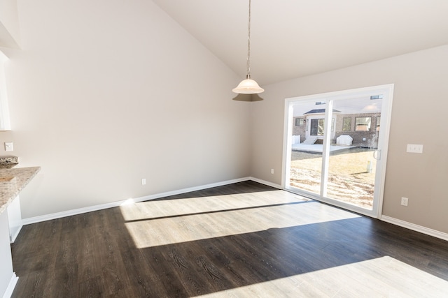 unfurnished dining area featuring vaulted ceiling, dark wood-style flooring, and baseboards