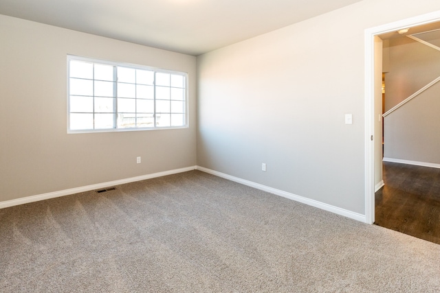 unfurnished room with baseboards, visible vents, and dark carpet