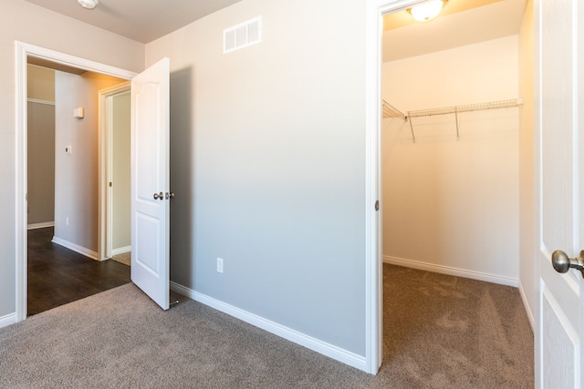 unfurnished bedroom with dark carpet, visible vents, and baseboards