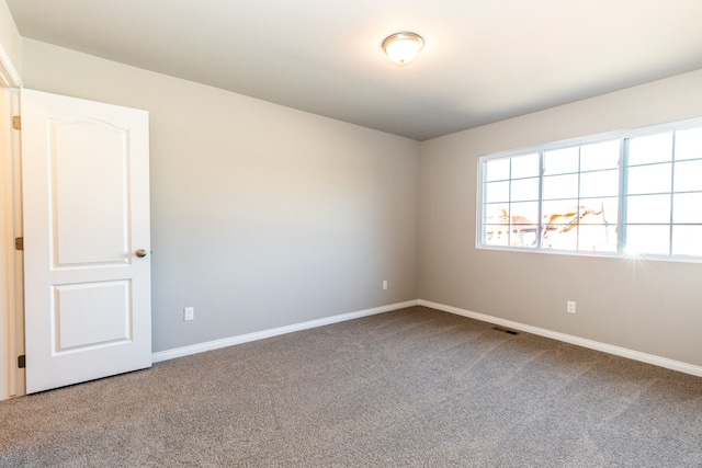 spare room featuring carpet floors, visible vents, and baseboards