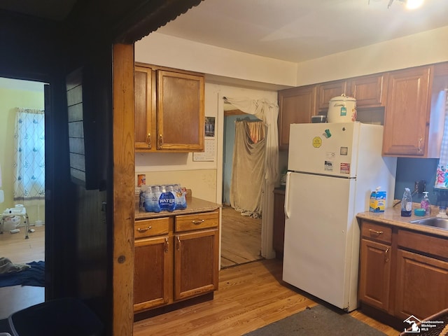 kitchen featuring sink, light hardwood / wood-style floors, and white fridge