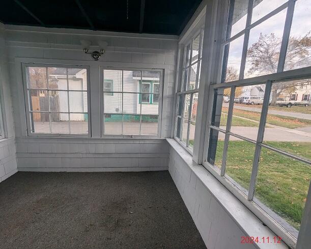 216 W Clark St, Jackson, MI 49203 - unfurnished sunroom with healthy amount of natural light, concrete block wall, and carpet floors