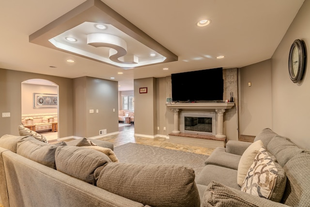 living room with a tray ceiling and a large fireplace