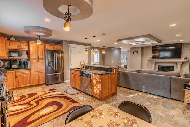 kitchen featuring a kitchen island with sink, hanging light fixtures, stainless steel appliances, and sink