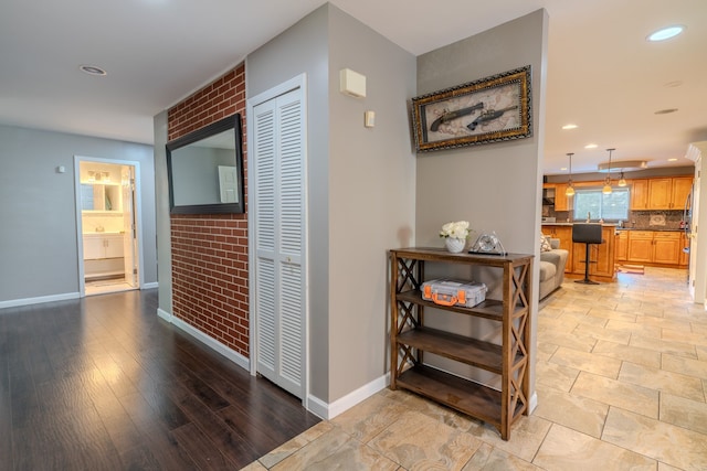 hall featuring brick wall and light wood-type flooring