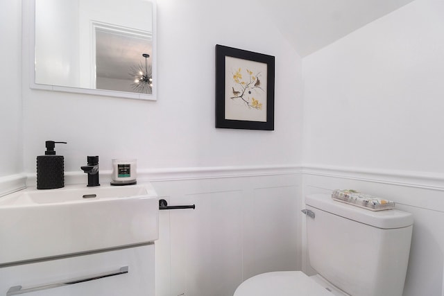 bathroom with vanity, toilet, and lofted ceiling