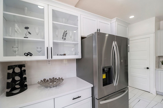 kitchen with backsplash, stainless steel fridge with ice dispenser, and white cabinets