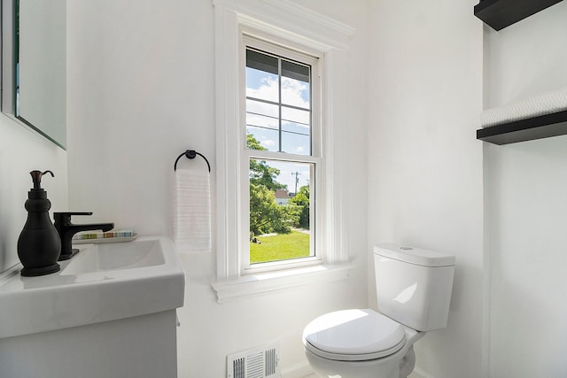 bathroom with toilet, a wealth of natural light, and sink