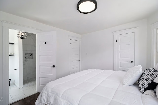 bedroom featuring a chandelier, dark hardwood / wood-style flooring, and ensuite bath