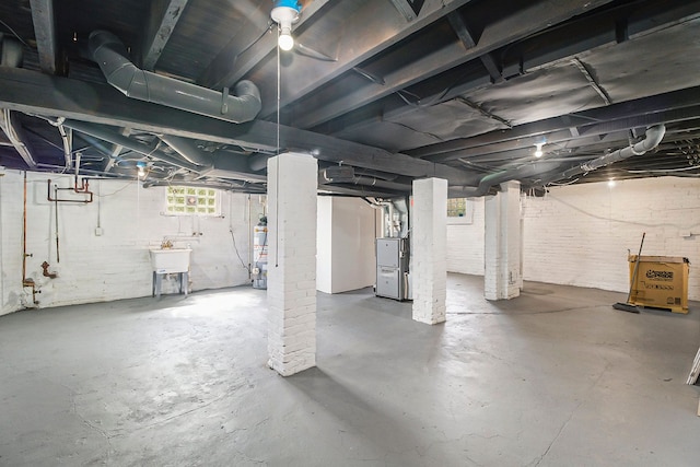 basement featuring gas water heater, heating unit, and sink