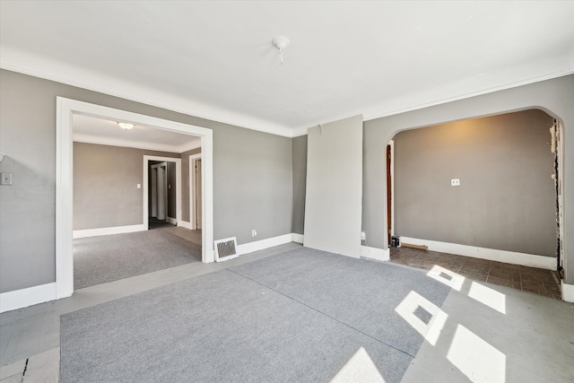 spare room featuring arched walkways, visible vents, crown molding, and baseboards