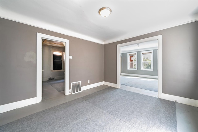 unfurnished room with baseboards, visible vents, and ornamental molding