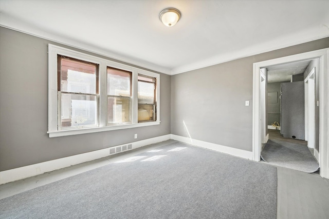 empty room featuring visible vents, baseboards, and carpet