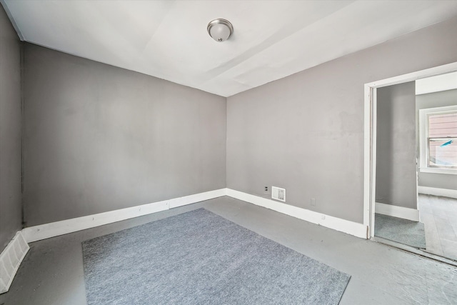 spare room featuring visible vents, baseboards, and concrete floors