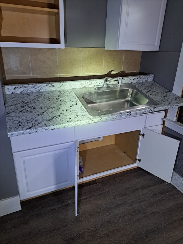 kitchen with a sink, dark wood-style floors, white cabinetry, light countertops, and decorative backsplash