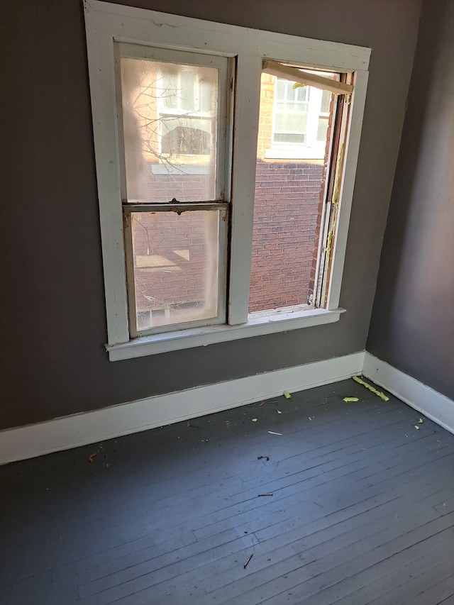 empty room with baseboards and wood-type flooring