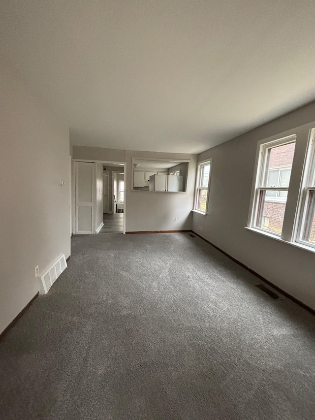 unfurnished living room with dark carpet and a wealth of natural light