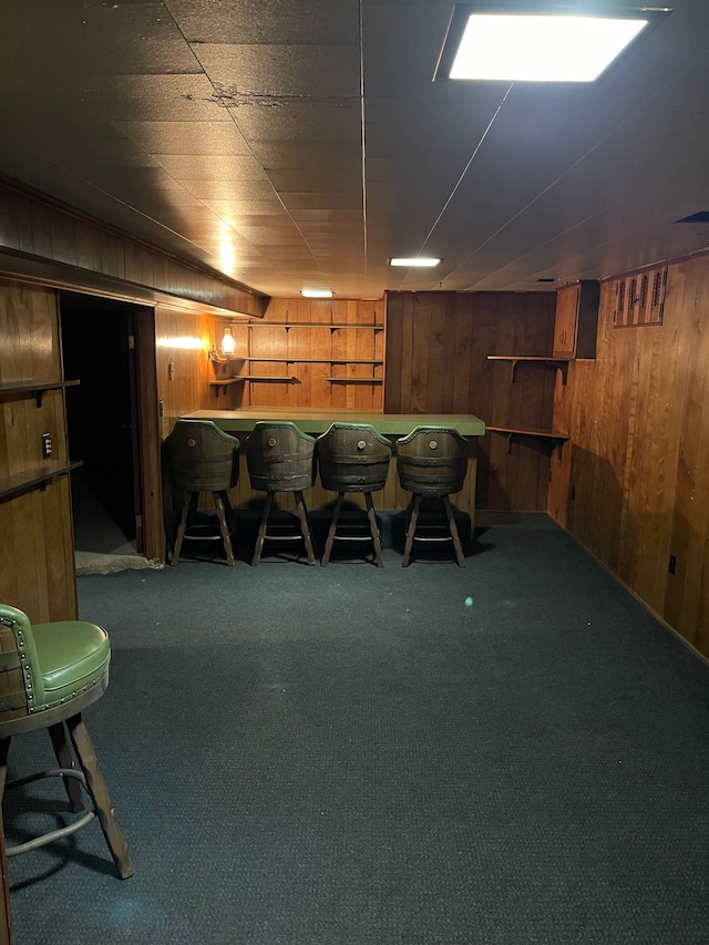 interior space featuring bar, dark colored carpet, and wood walls