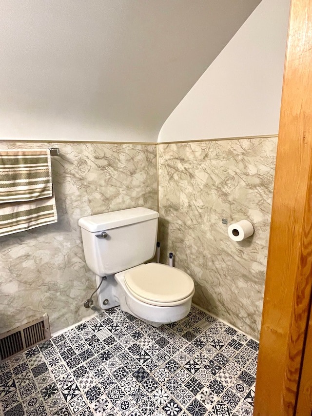 bathroom featuring tile patterned flooring, toilet, and tile walls