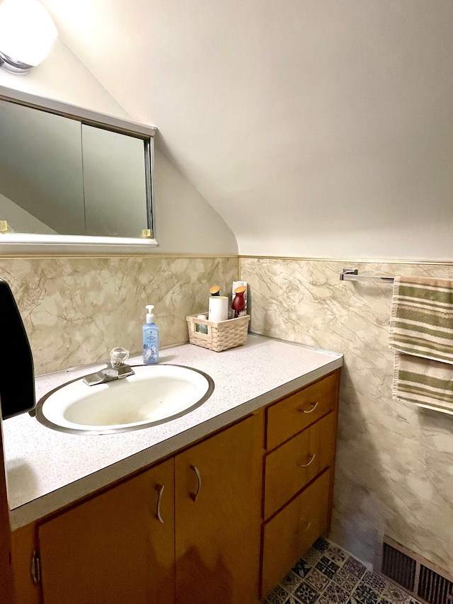 bathroom with tile walls, vanity, and vaulted ceiling