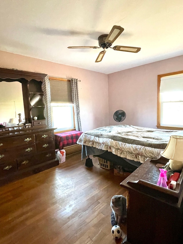 bedroom with multiple windows, ceiling fan, and wood-type flooring