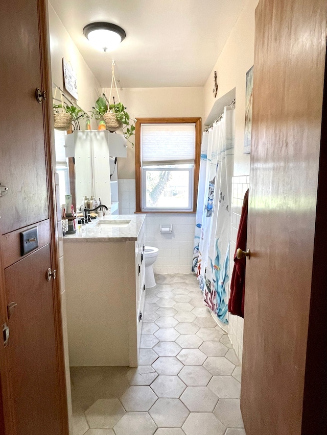 bathroom featuring tile patterned flooring, vanity, toilet, and tile walls