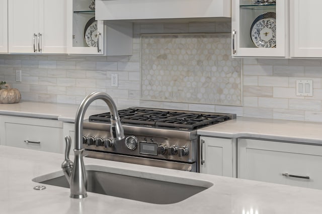 kitchen featuring white cabinets, ventilation hood, sink, tasteful backsplash, and light stone counters