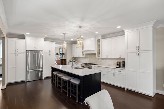 kitchen featuring appliances with stainless steel finishes, white cabinetry, pendant lighting, and an island with sink