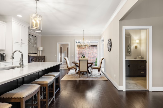 kitchen with dark wood-type flooring, an inviting chandelier, white cabinets, sink, and decorative light fixtures