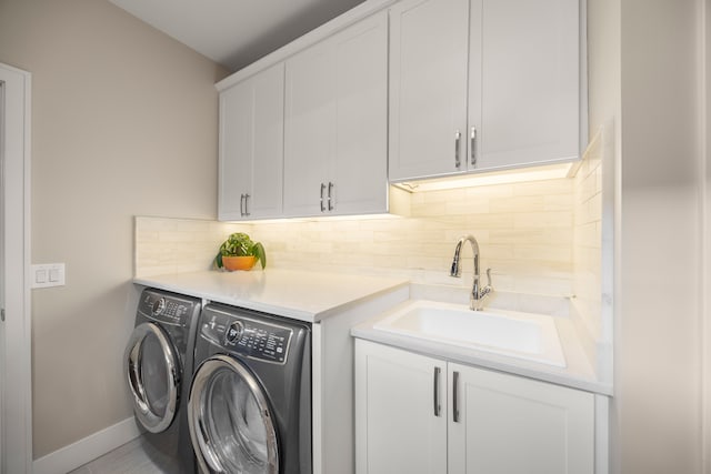 clothes washing area featuring cabinets, washing machine and dryer, and sink