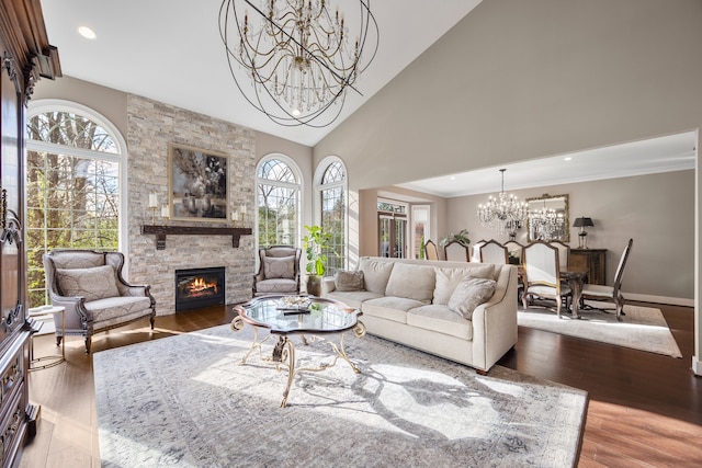 living room with a chandelier, high vaulted ceiling, hardwood / wood-style flooring, and a stone fireplace