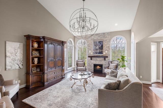 living room with a stone fireplace, dark wood-type flooring, high vaulted ceiling, and an inviting chandelier