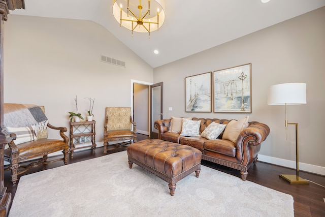 living room with a notable chandelier, dark wood-type flooring, and vaulted ceiling