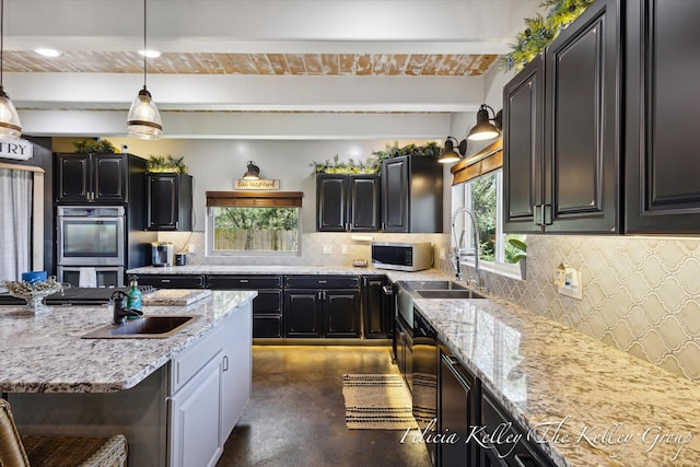 kitchen featuring tasteful backsplash, light stone counters, stainless steel appliances, sink, and decorative light fixtures