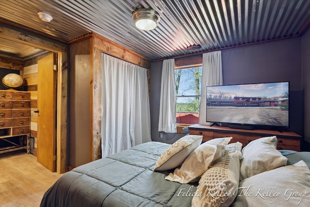 bedroom with wood walls and light hardwood / wood-style floors