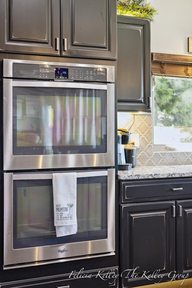 kitchen featuring decorative backsplash, light stone counters, and double oven