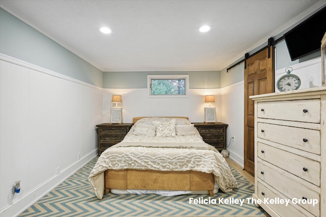 bedroom with a barn door and crown molding