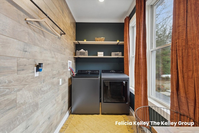 clothes washing area with washing machine and dryer and wooden walls