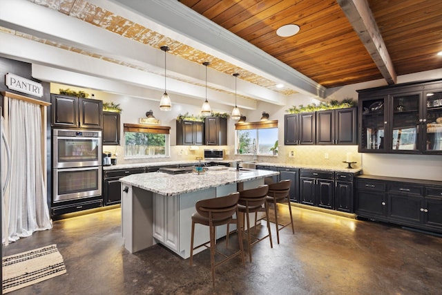 kitchen featuring stainless steel double oven, tasteful backsplash, an island with sink, a kitchen bar, and wood ceiling