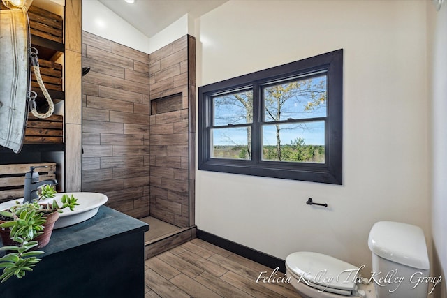 bathroom featuring walk in shower, vanity, vaulted ceiling, hardwood / wood-style flooring, and toilet