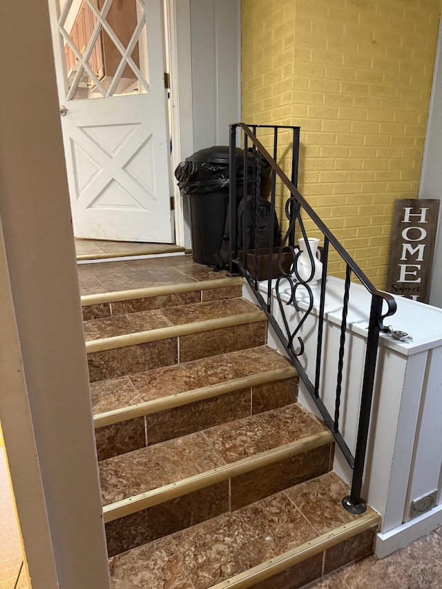 stairway featuring brick wall