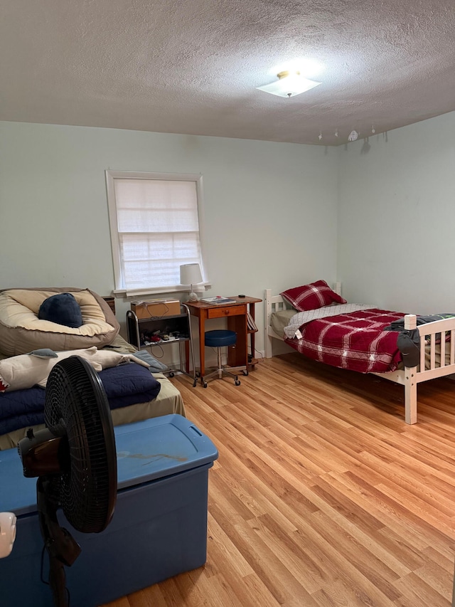 bedroom with light hardwood / wood-style floors and a textured ceiling