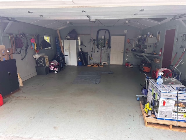 garage featuring a garage door opener and white fridge with ice dispenser
